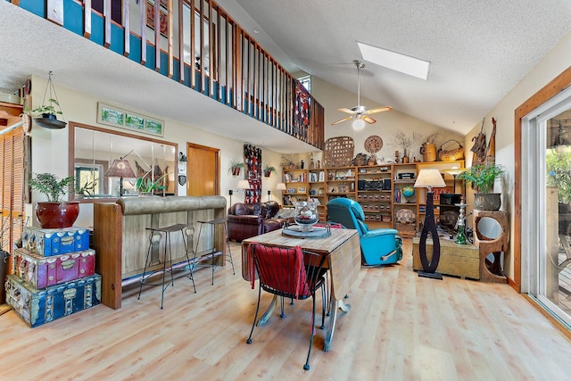 dining space featuring ceiling fan, vaulted ceiling with skylight, a healthy amount of sunlight, and wood-type flooring