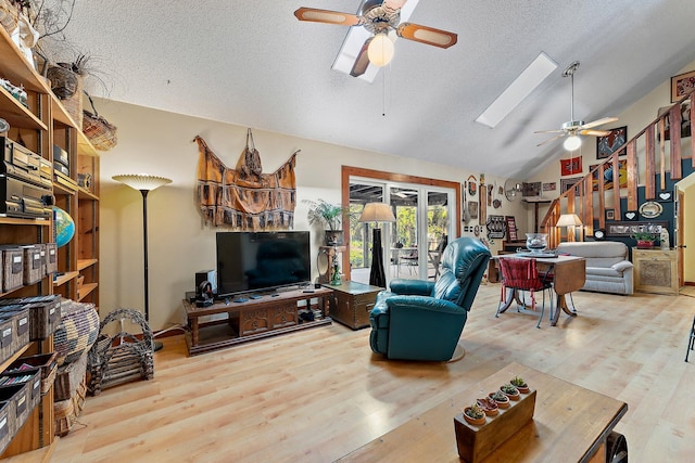 living room with vaulted ceiling with skylight, a textured ceiling, and hardwood / wood-style flooring