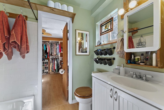 full bathroom featuring vanity, hardwood / wood-style flooring, toilet, a textured ceiling, and shower / bath combination