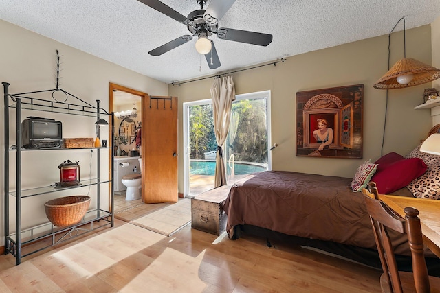 bedroom featuring light wood-type flooring, ensuite bathroom, ceiling fan with notable chandelier, access to outside, and a textured ceiling