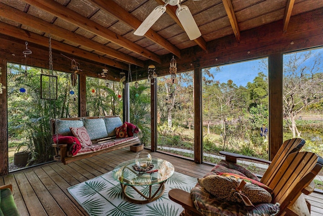 unfurnished sunroom featuring beamed ceiling, plenty of natural light, ceiling fan, and wooden ceiling