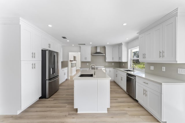 kitchen featuring a center island with sink, wall chimney exhaust hood, white cabinetry, and appliances with stainless steel finishes