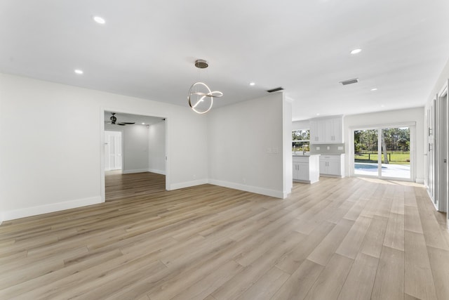 interior space featuring ceiling fan with notable chandelier and light hardwood / wood-style flooring