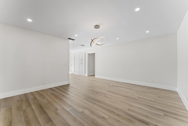 empty room featuring light hardwood / wood-style floors and a notable chandelier