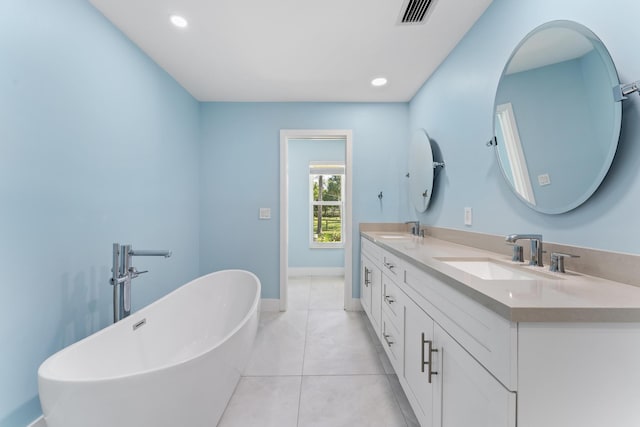 bathroom with a washtub, vanity, and tile patterned flooring