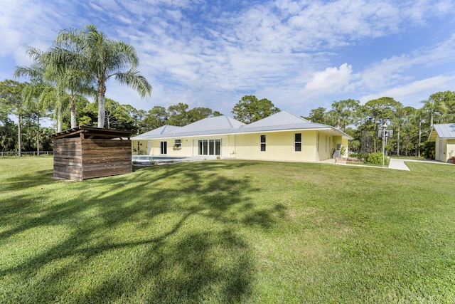 rear view of property featuring a yard and a swimming pool