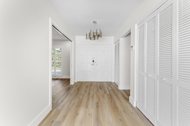 corridor with a chandelier and light hardwood / wood-style flooring