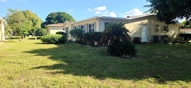 view of side of property with central AC and a lawn