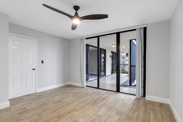 empty room featuring ceiling fan, expansive windows, and light hardwood / wood-style floors