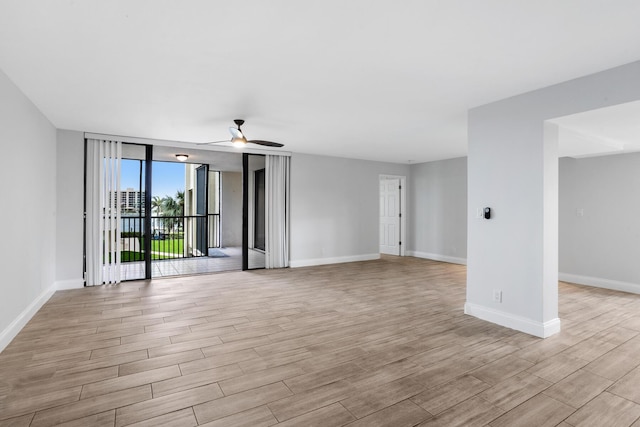 empty room with ceiling fan and a wall of windows