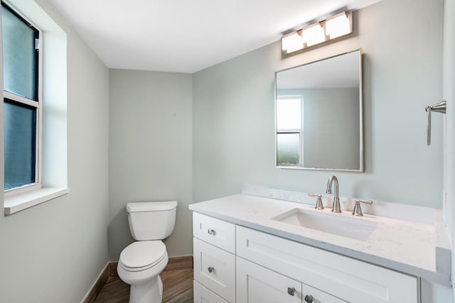 bathroom with wood-type flooring, vanity, and toilet