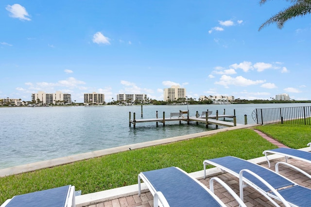 view of dock with a patio area, a water view, and a yard