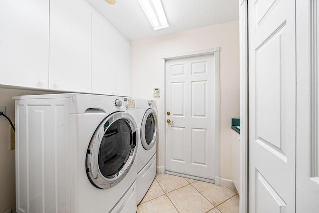 laundry room featuring washing machine and clothes dryer, light tile patterned flooring, cabinets, and a textured ceiling