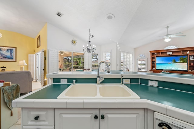 kitchen featuring white cabinetry, sink, ceiling fan with notable chandelier, and vaulted ceiling