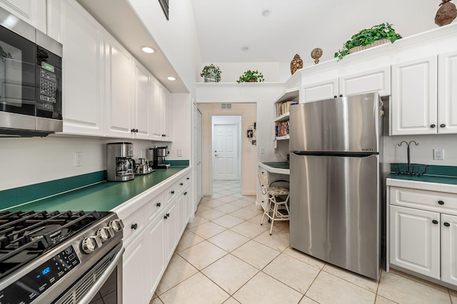 kitchen featuring white cabinets, stainless steel appliances, and light tile patterned floors