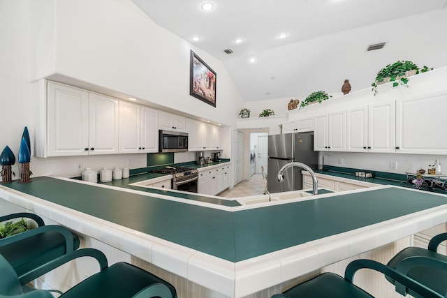 kitchen with white cabinets, a kitchen breakfast bar, kitchen peninsula, and stainless steel appliances