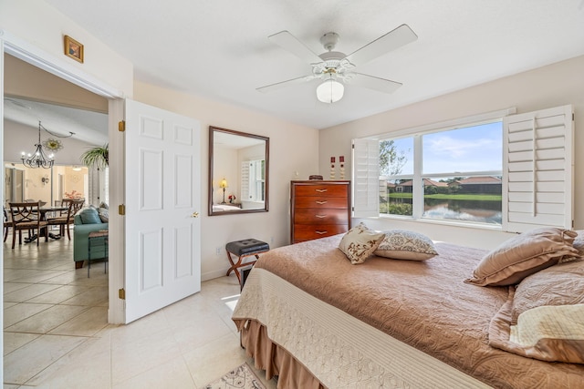 tiled bedroom with ceiling fan with notable chandelier and a water view