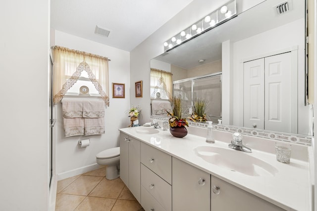 bathroom featuring tile patterned floors, a shower with door, vanity, and toilet