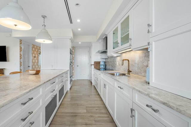 kitchen with pendant lighting, backsplash, white cabinets, sink, and light stone counters