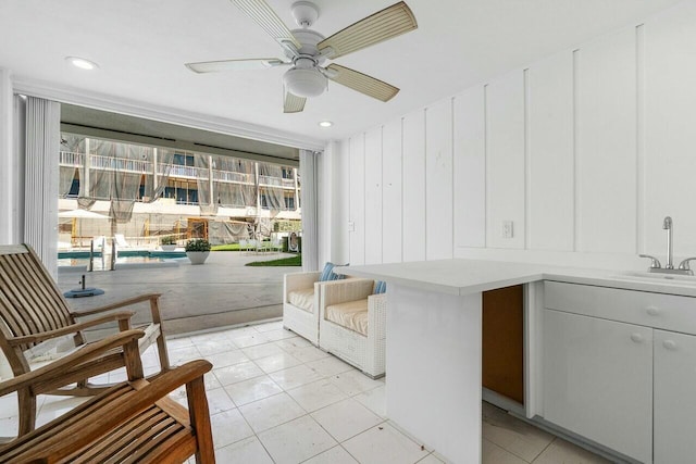 living area with ceiling fan, sink, and light tile patterned flooring