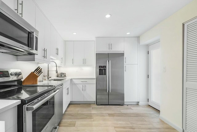 kitchen with appliances with stainless steel finishes, white cabinetry, and sink