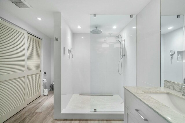 bathroom featuring hardwood / wood-style floors, vanity, and tiled shower