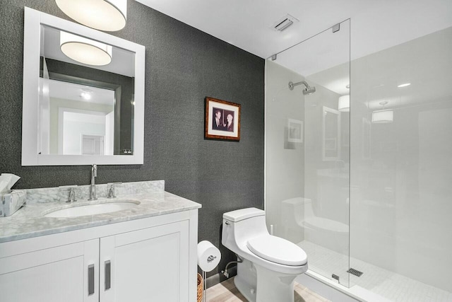 bathroom with walk in shower, vanity, and toilet