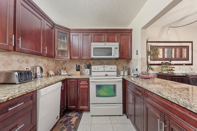 kitchen featuring light stone countertops, light tile patterned floors, white appliances, and sink