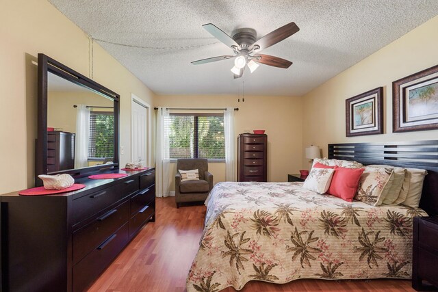 bedroom featuring ceiling fan, hardwood / wood-style floors, and a textured ceiling