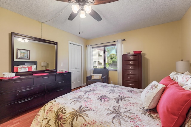 bedroom with light wood-type flooring, a textured ceiling, a closet, and ceiling fan