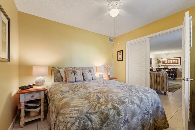 bedroom featuring a textured ceiling, a closet, ceiling fan, and light tile patterned flooring