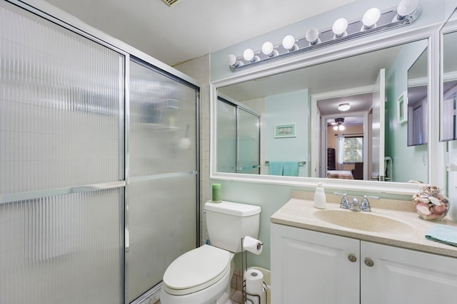 bathroom with vanity, toilet, a shower with door, and ceiling fan