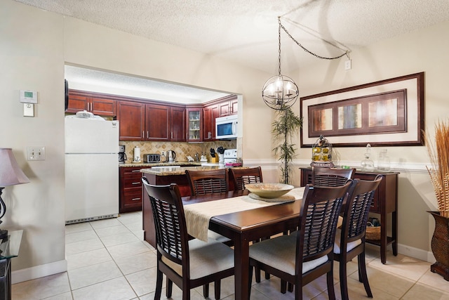 tiled dining space with a textured ceiling and a notable chandelier