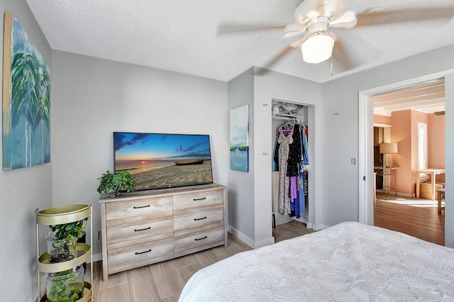 bedroom featuring a textured ceiling, a closet, ceiling fan, and light hardwood / wood-style floors