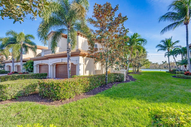 view of front of property with a water view, a front yard, and a garage