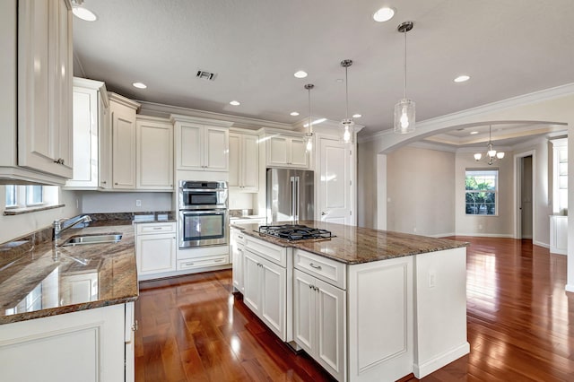 kitchen with appliances with stainless steel finishes, a kitchen island, hanging light fixtures, and sink