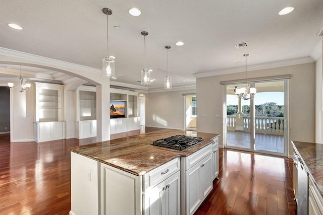 kitchen with an inviting chandelier, gas cooktop, dark stone counters, decorative light fixtures, and a kitchen island