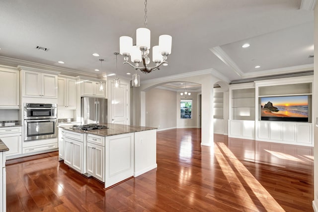 kitchen featuring hanging light fixtures, stainless steel appliances, an inviting chandelier, dark stone counters, and a kitchen island