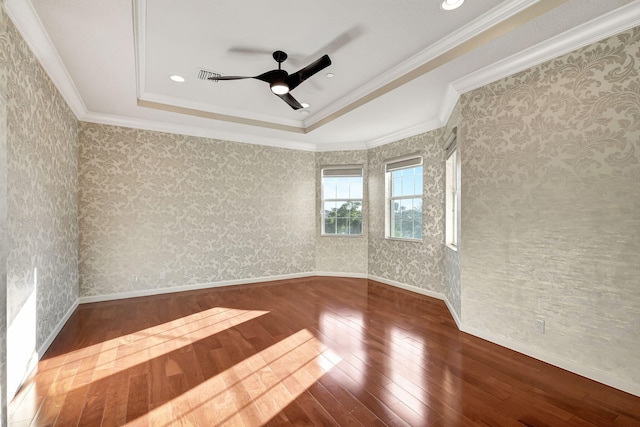 empty room featuring a raised ceiling, ceiling fan, wood-type flooring, and ornamental molding