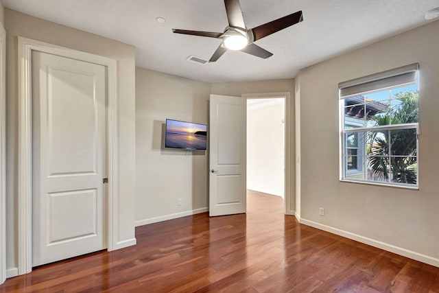 unfurnished bedroom with ceiling fan and dark wood-type flooring