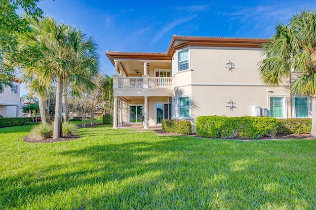 back of property with a lawn, ceiling fan, and a balcony