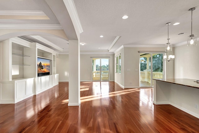 unfurnished living room featuring an inviting chandelier, built in shelves, ornamental molding, a textured ceiling, and dark hardwood / wood-style flooring