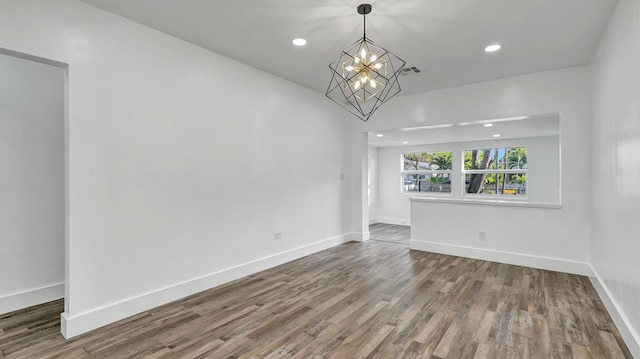 spare room featuring hardwood / wood-style flooring and an inviting chandelier