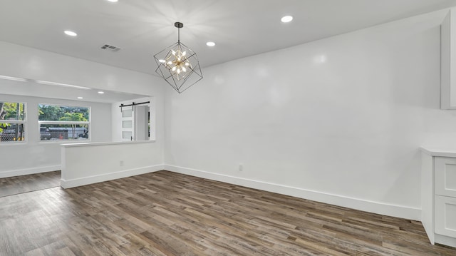 interior space featuring hardwood / wood-style flooring, a barn door, and an inviting chandelier