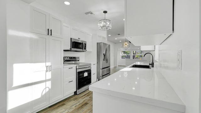 kitchen featuring decorative light fixtures, sink, white cabinetry, and stainless steel appliances