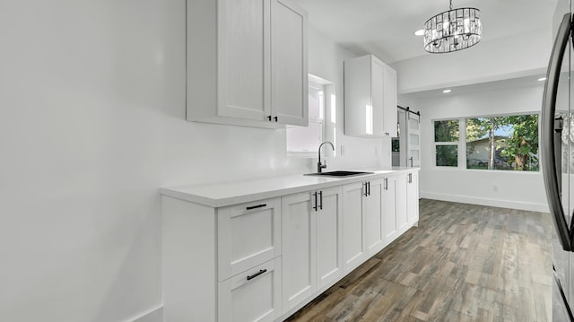 kitchen with white cabinets, sink, a barn door, decorative light fixtures, and a chandelier