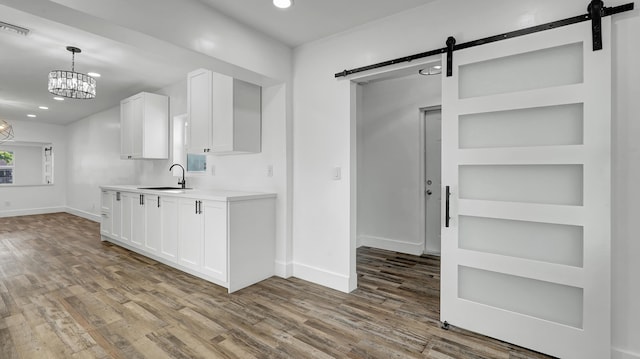 kitchen featuring a barn door, white cabinetry, sink, and an inviting chandelier