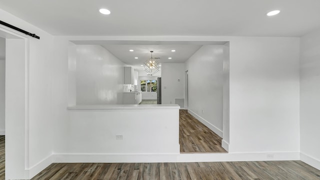 kitchen featuring kitchen peninsula, a barn door, decorative light fixtures, a chandelier, and hardwood / wood-style floors