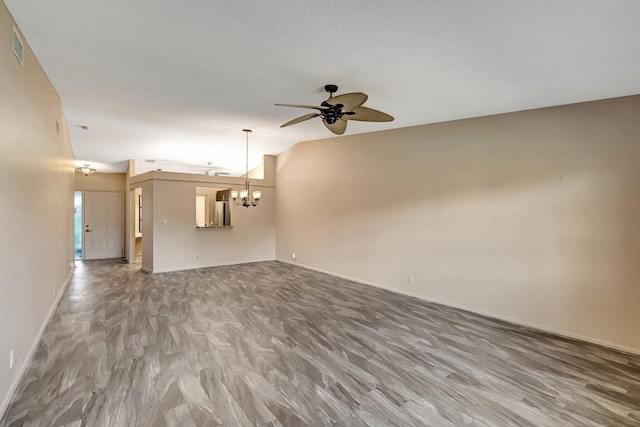 unfurnished living room featuring ceiling fan with notable chandelier