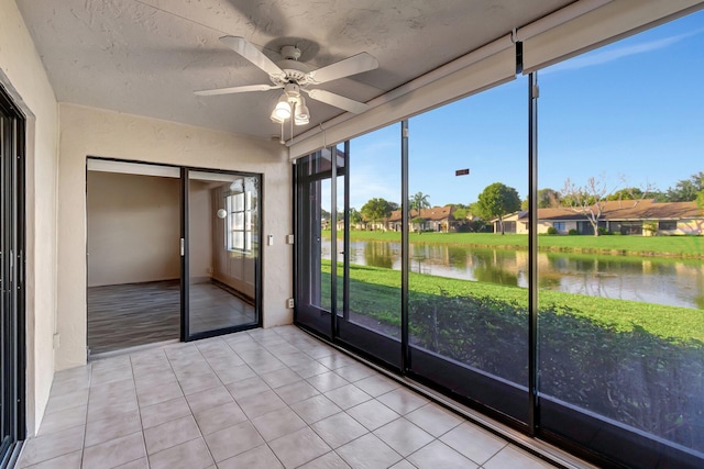 unfurnished sunroom with ceiling fan and a water view